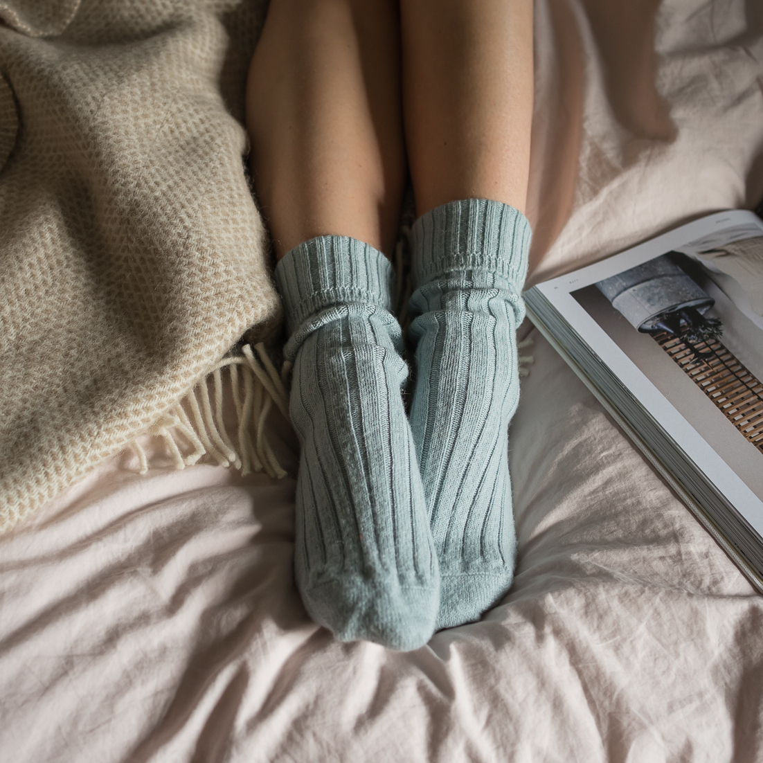 Blue knitted ankle socks, modelled with blankets